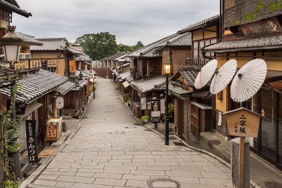 An empty lane with wooden houses and paper umbrellas in Kyoto