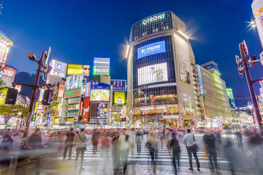 The Shibuya crossing in Tokyo at blue hour, people crossing in every direction