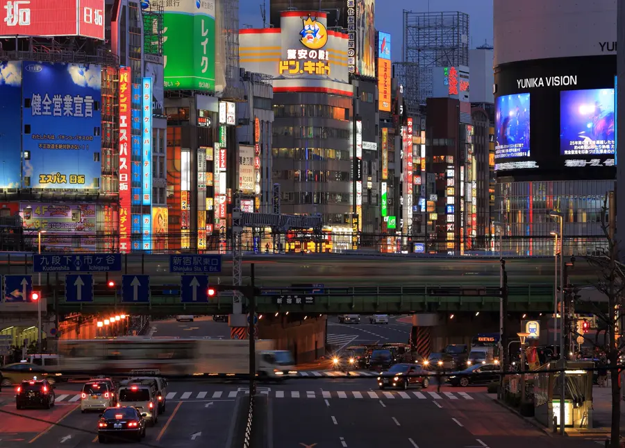 Traffic and neon signs on a street in Shinjuku at night